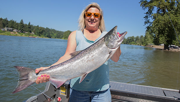 a happy lady holding a spring chinook salmon caught on the willamette river